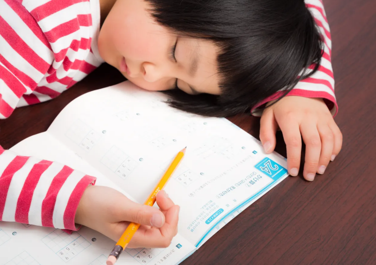 勉強中に疲れて居眠りする小学生